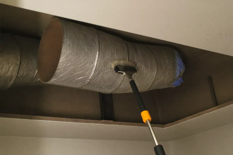 Rotary brush cleaning the inside of an opened insulated supply duct in a villa ceiling void